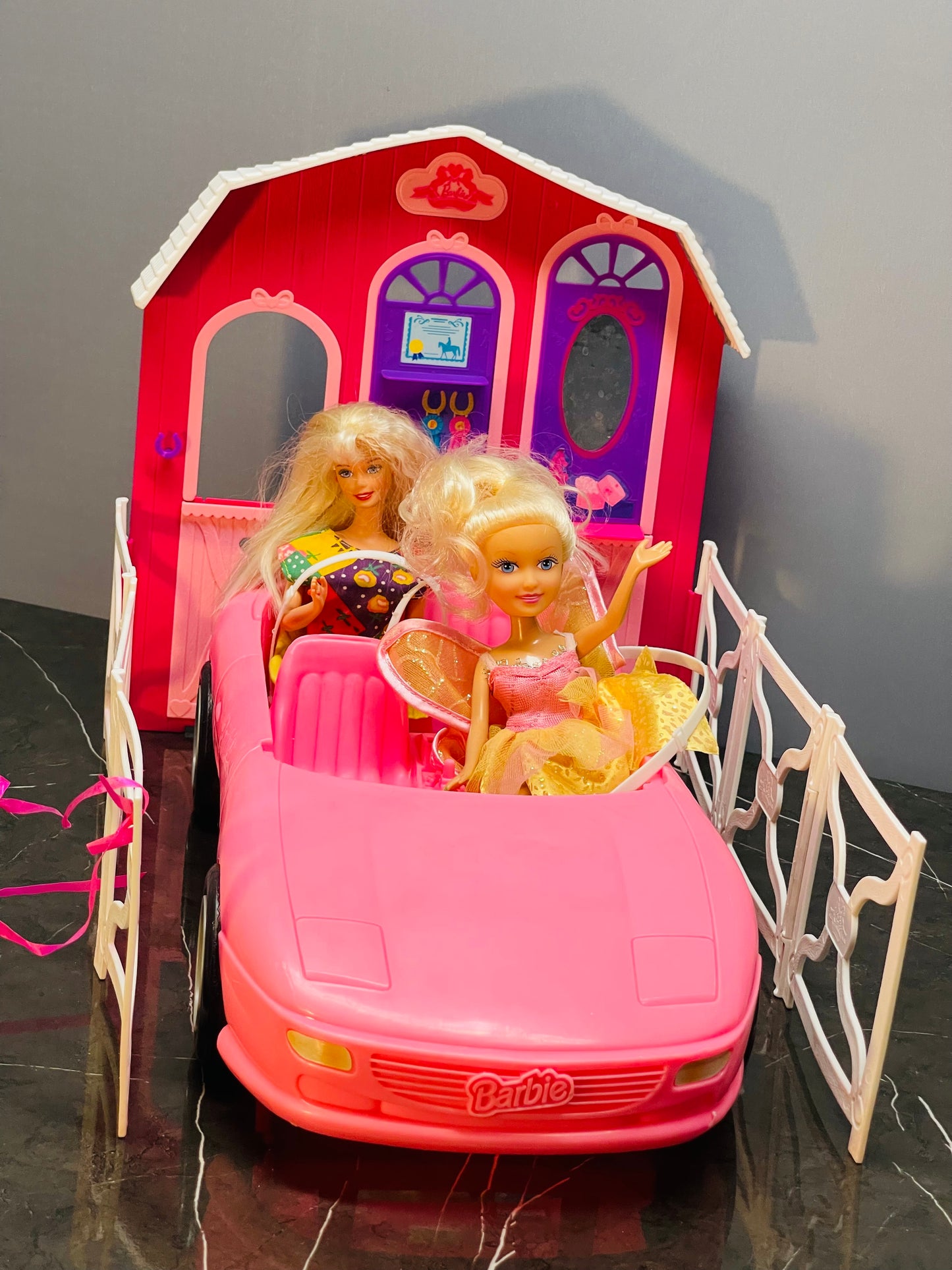 Barbie Glam Convertible car along with two Barbie dolls and a small playhouse.