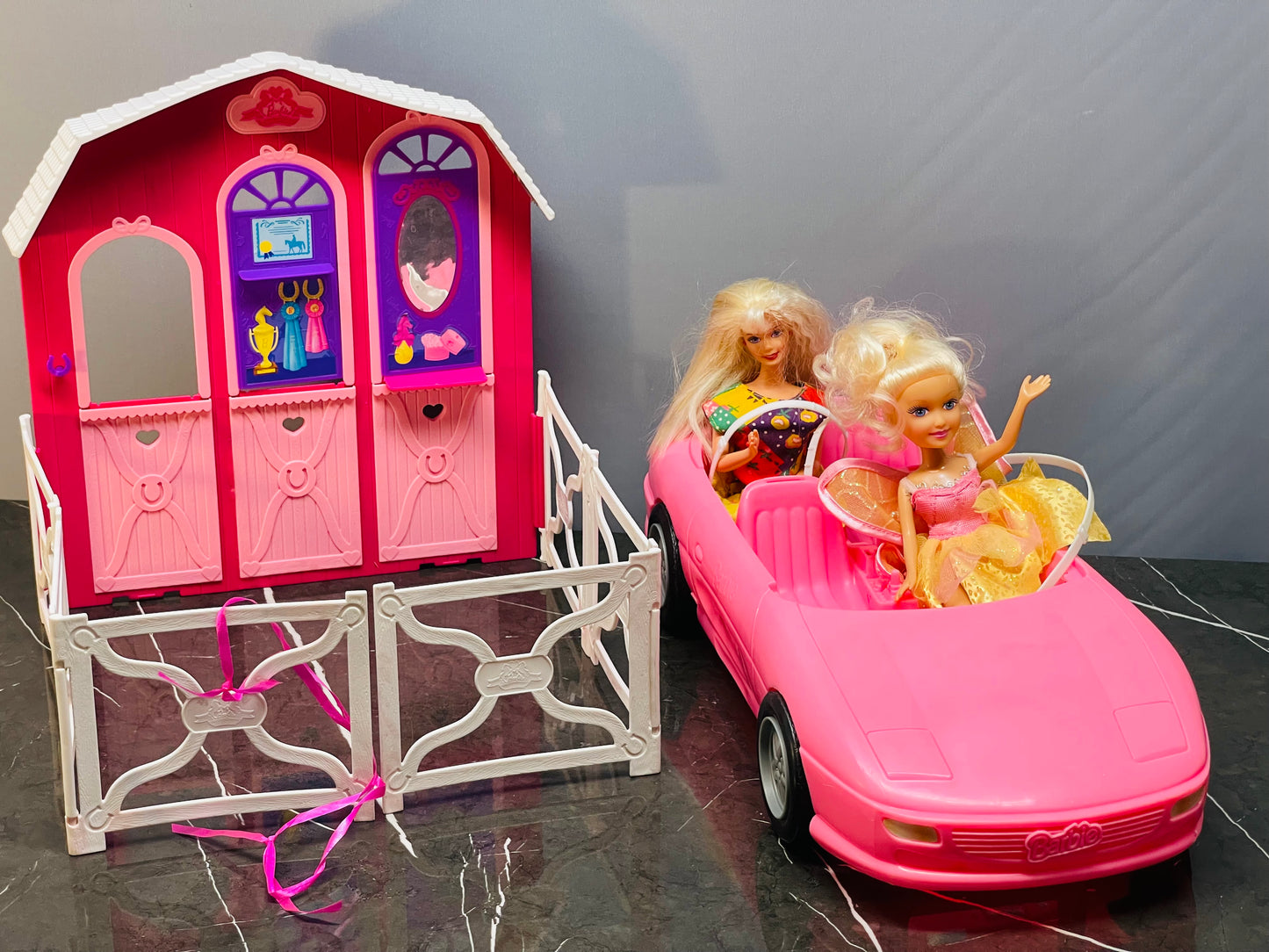 Barbie Glam Convertible car along with two Barbie dolls and a small playhouse.