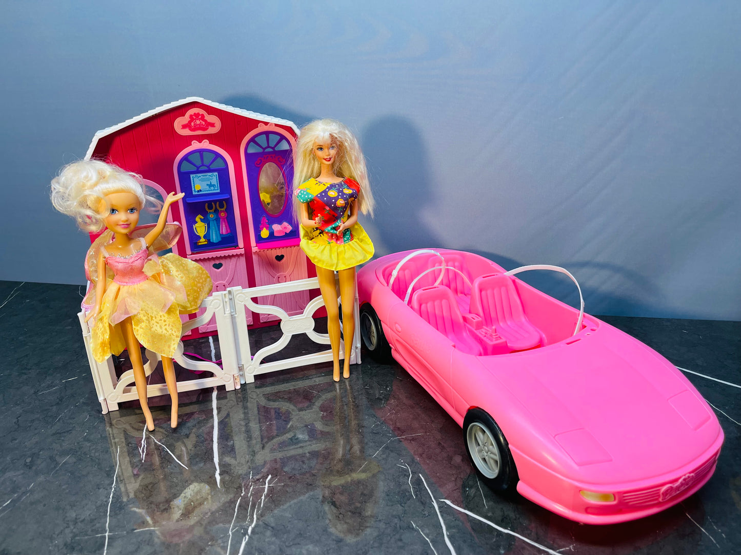 Barbie Glam Convertible car along with two Barbie dolls and a small playhouse.