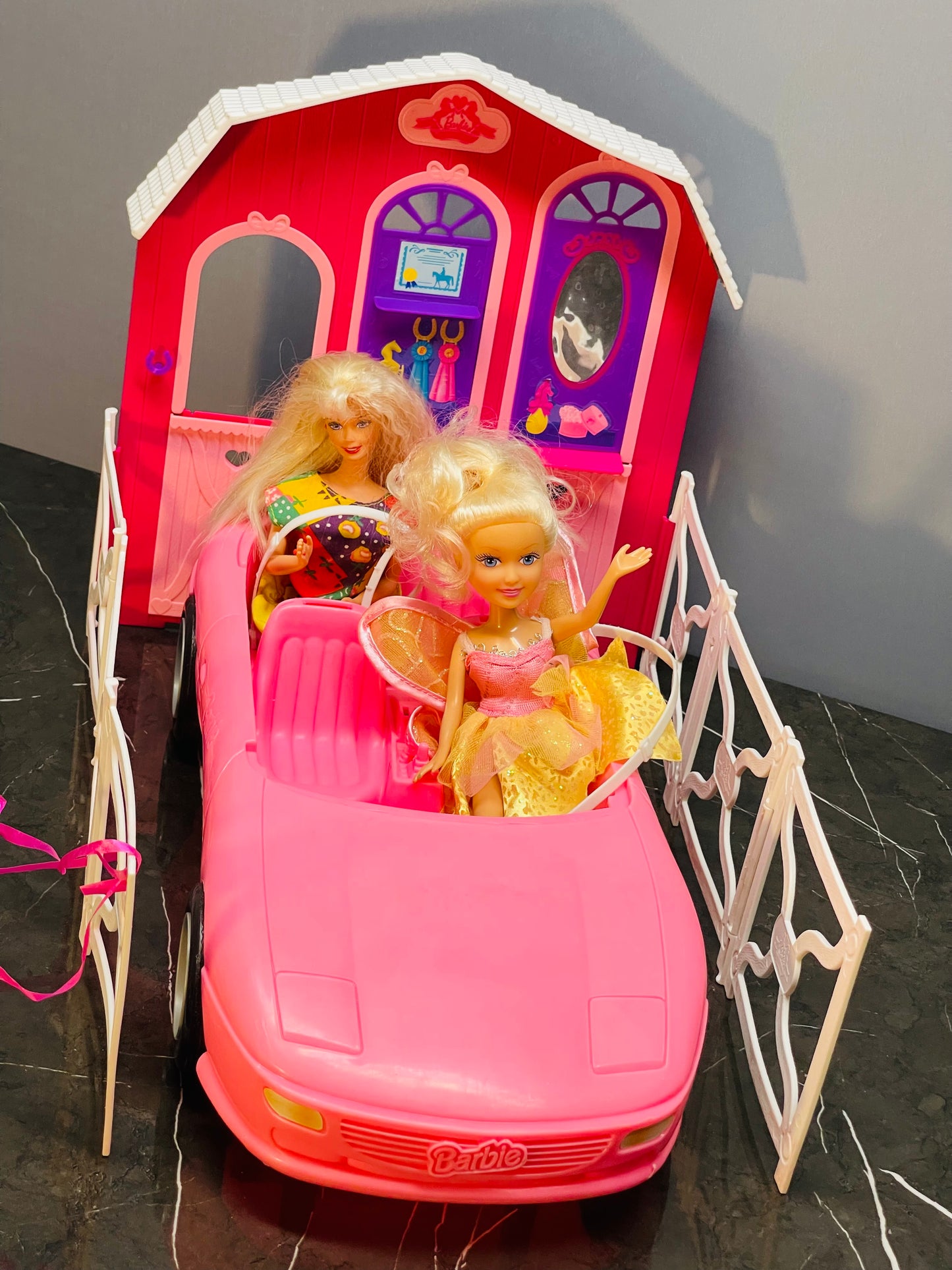 Barbie Glam Convertible car along with two Barbie dolls and a small playhouse.