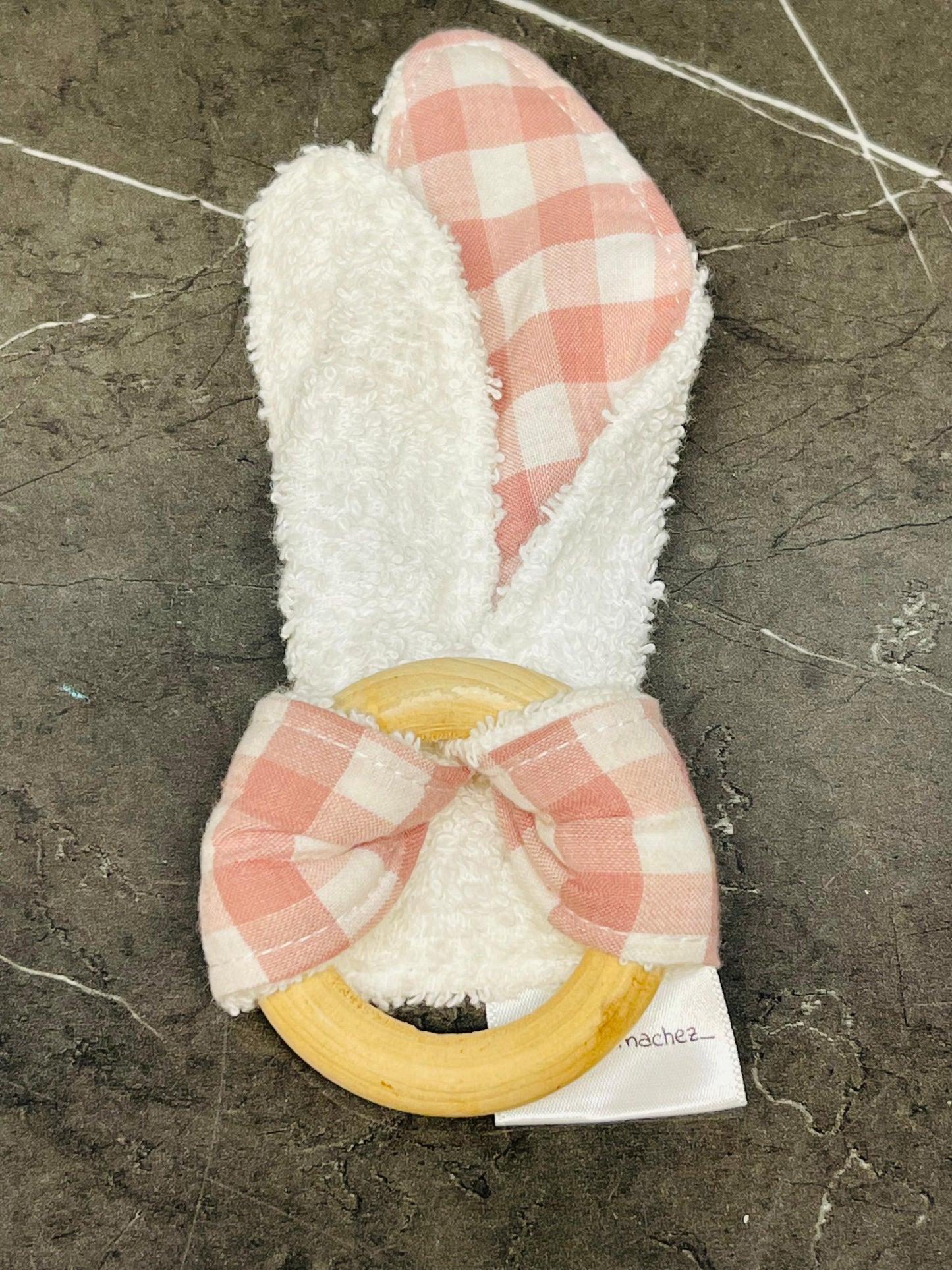Baby teething ring with fabric bunny ears and a bow.