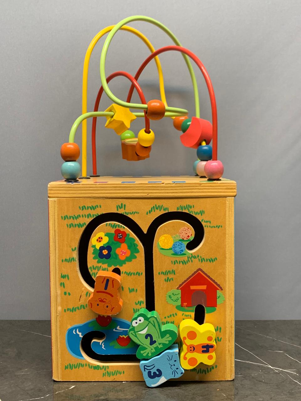 Wooden activity cube, a multi-sided toy.