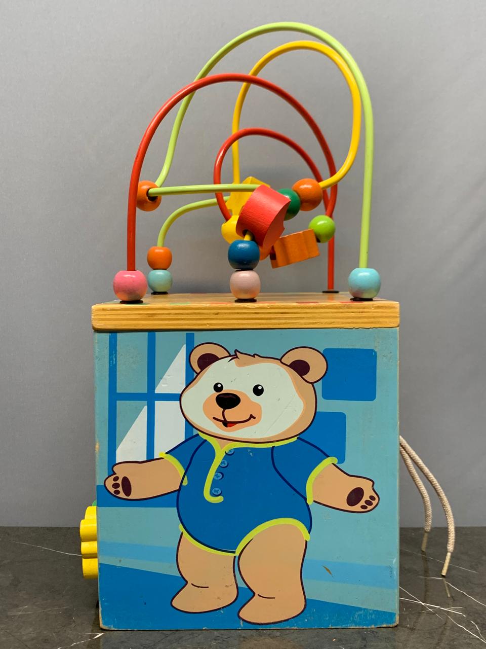 Wooden activity cube, a multi-sided toy.
