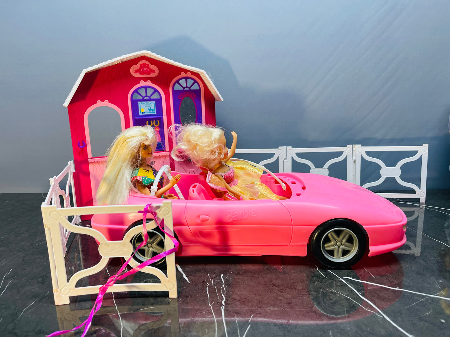 Barbie Glam Convertible car along with two Barbie dolls and a small playhouse.