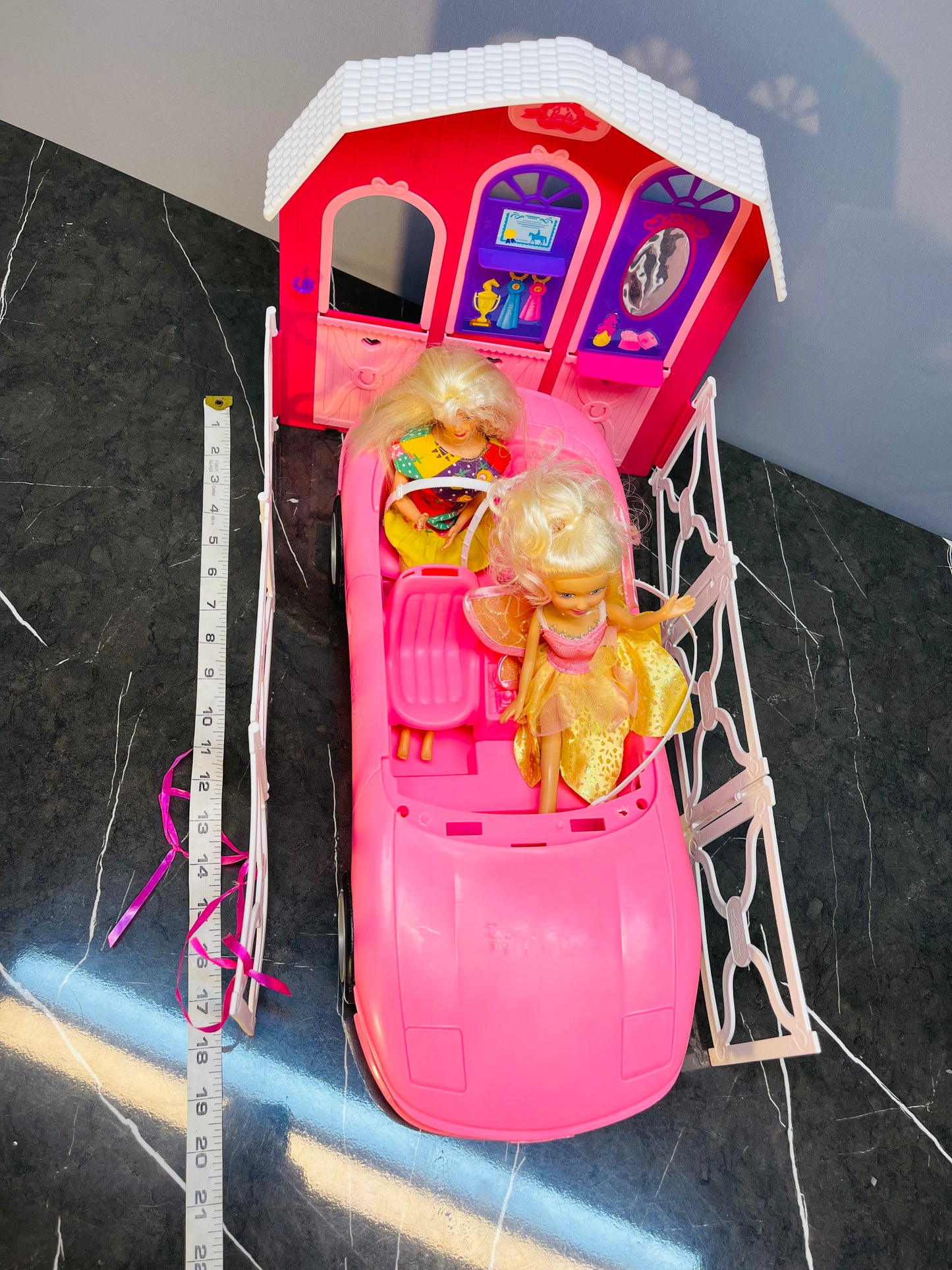 Barbie Glam Convertible car along with two Barbie dolls and a small playhouse.