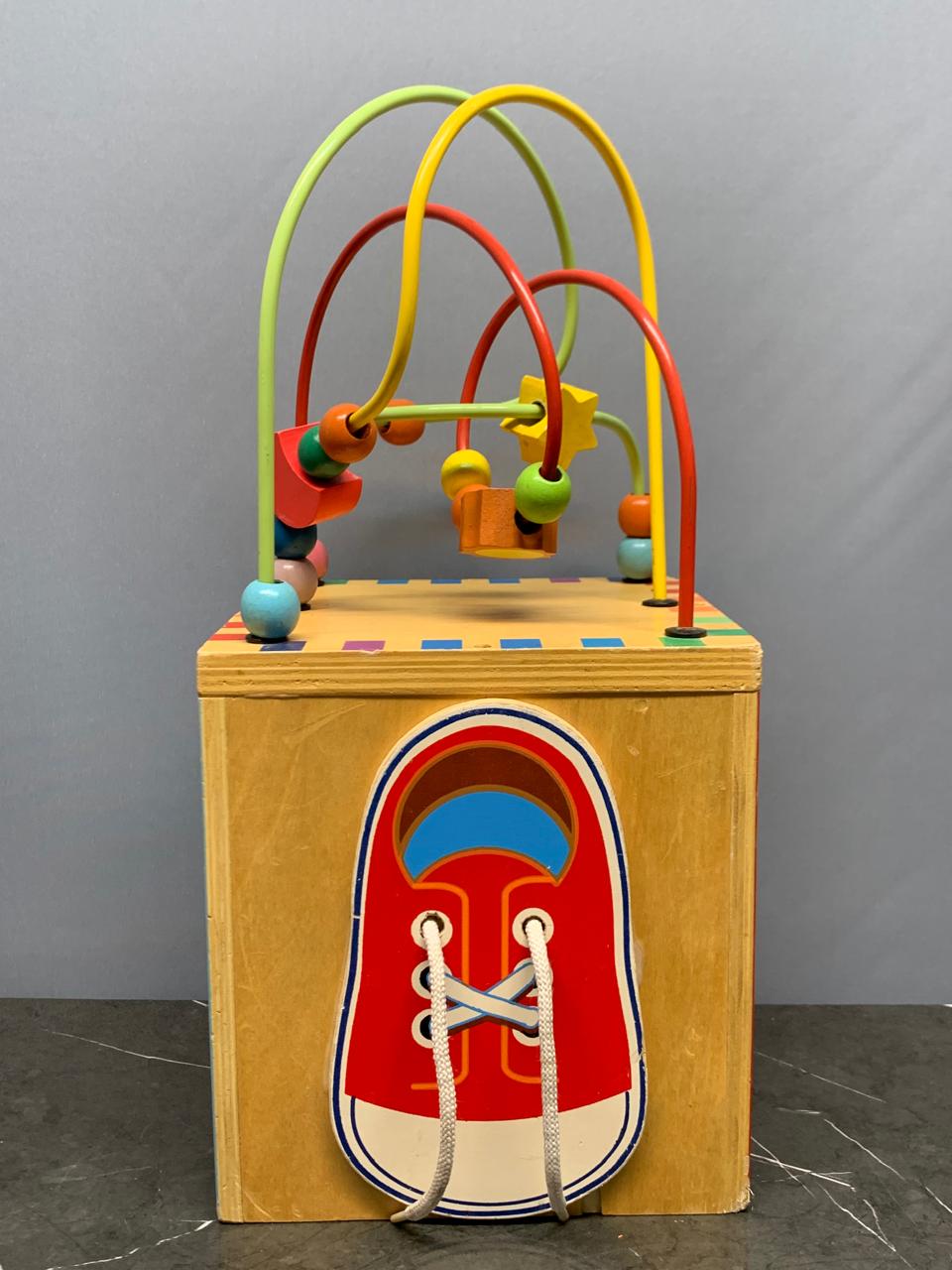Wooden activity cube, a multi-sided toy.